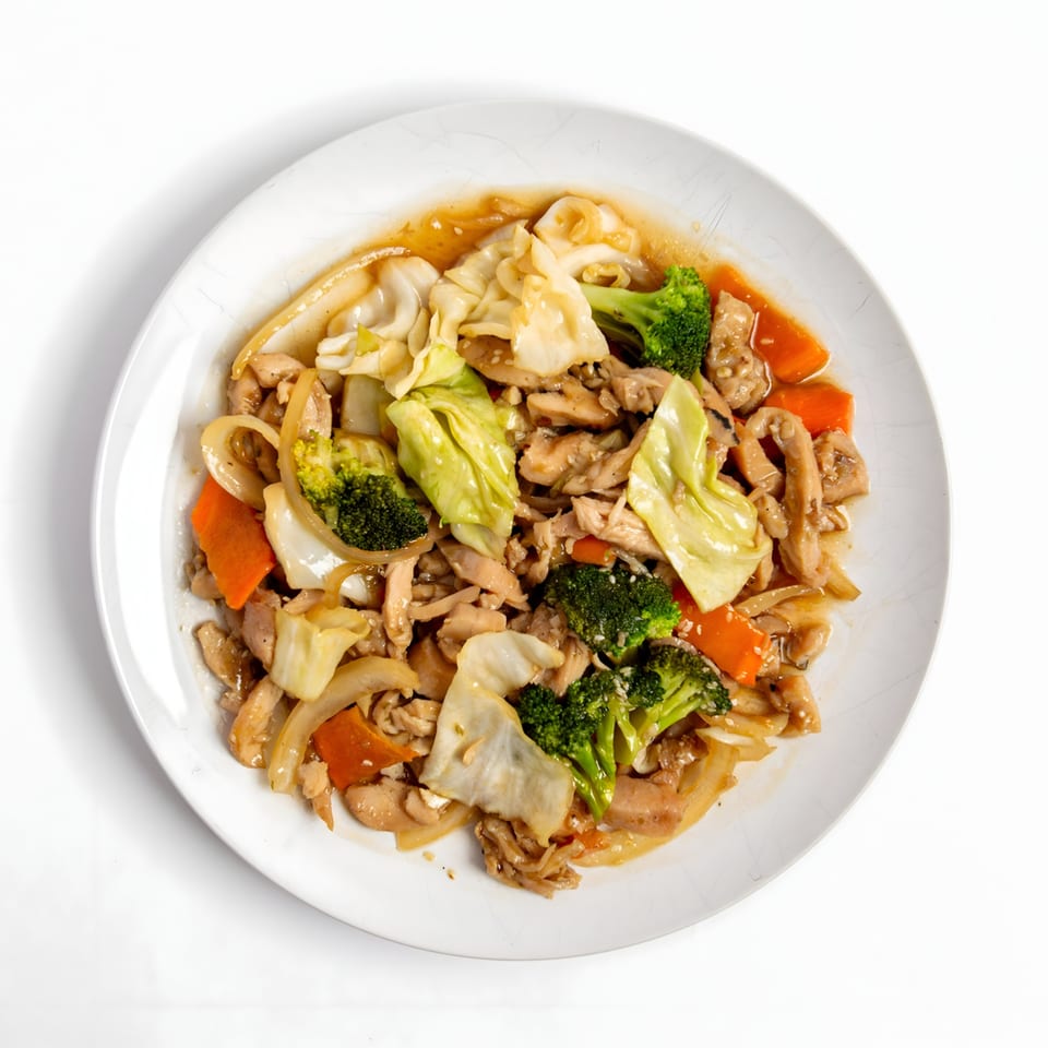 Asian stir-fry with chicken, broccoli, cabbage, carrots, and onions on a white plate.