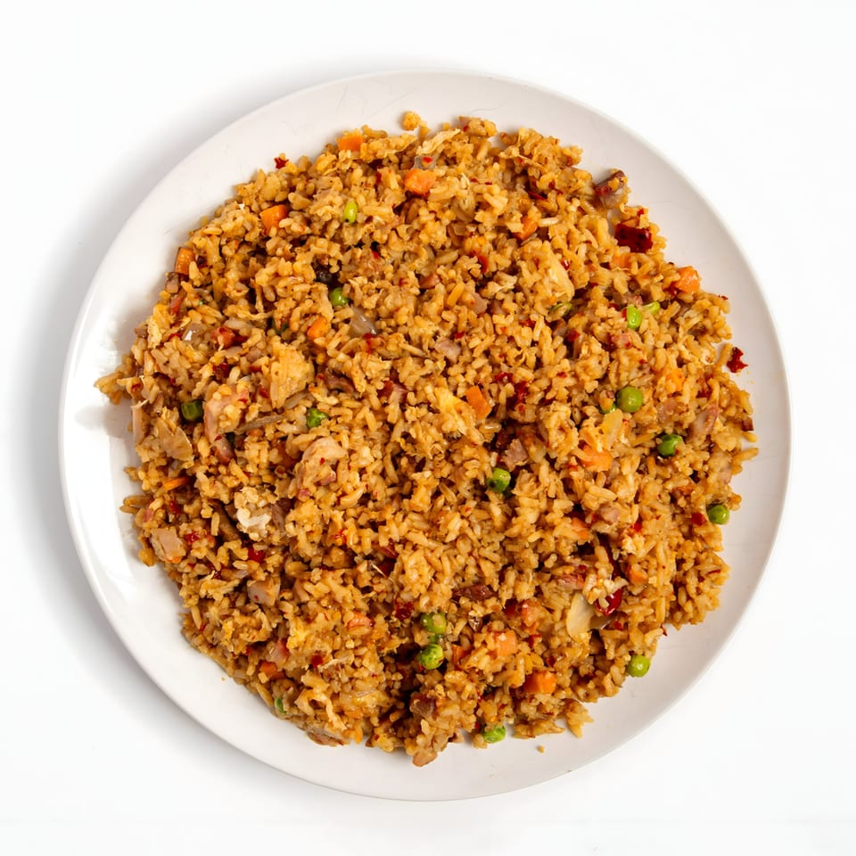 Overhead view of a white plate filled with chicken fried rice, peas, and carrots.