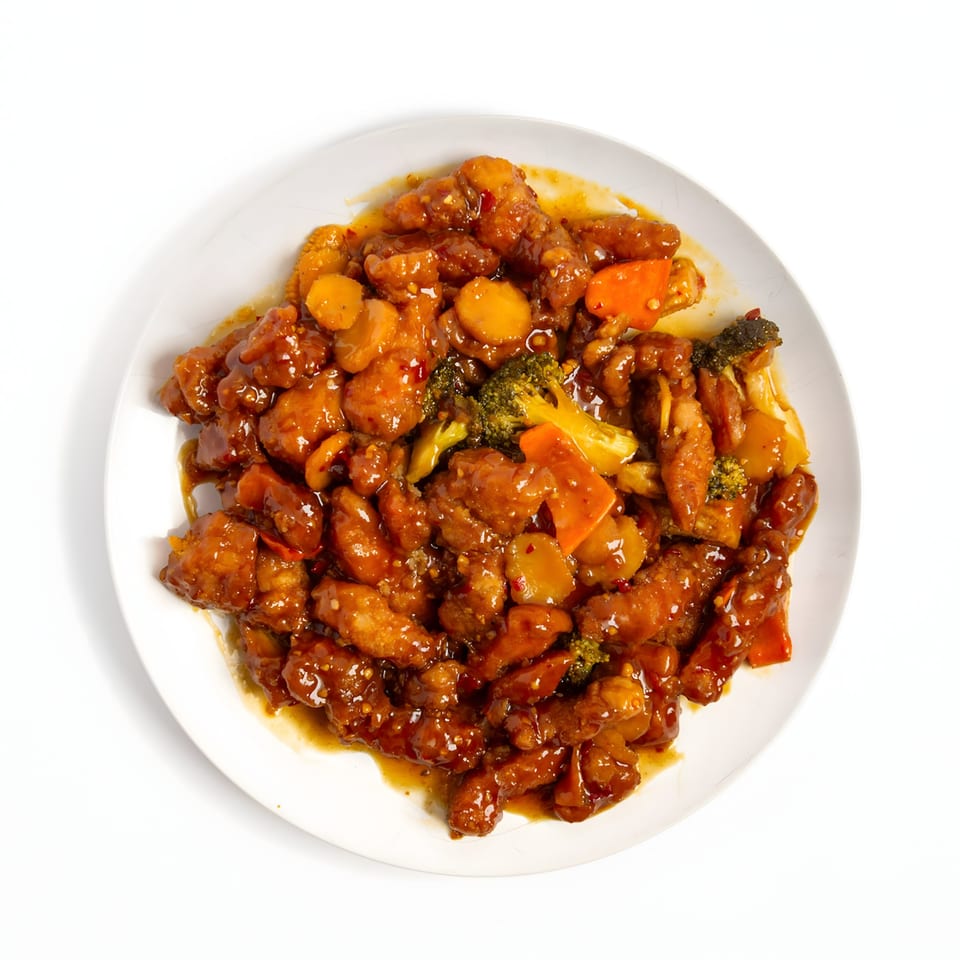 Sweet and sour chicken with broccoli, carrots, and water chestnuts on a white plate.