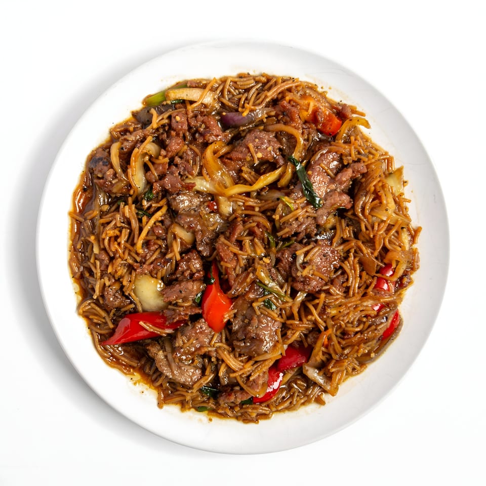 Asian beef and noodle dish with red bell peppers and onions on a white plate.